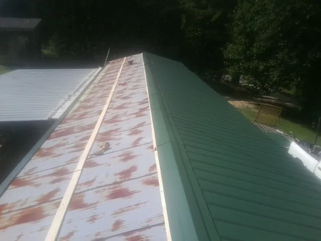 Old rusted panels beside newly installed green metal roofing — Wind Damage Roof Repair by Roofing Brothers in Seward